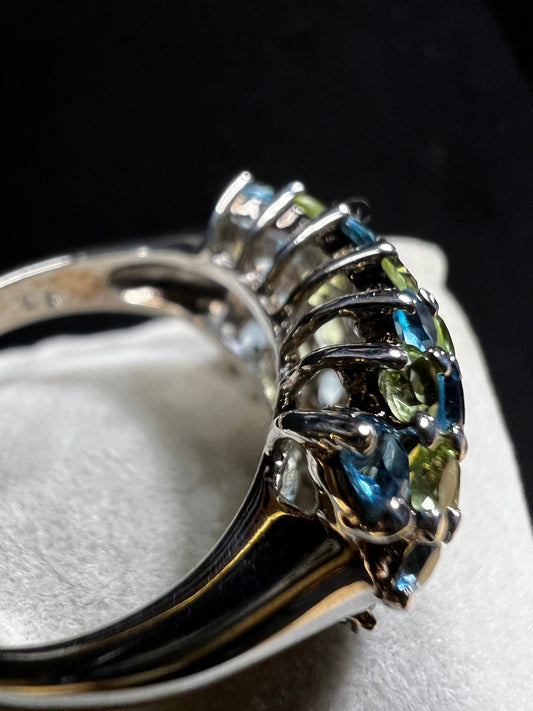 This sterling silver ring features over two dozen meticulously set blue spinel and green tourmaline stones, creating a vibrant interplay of color and brilliance.