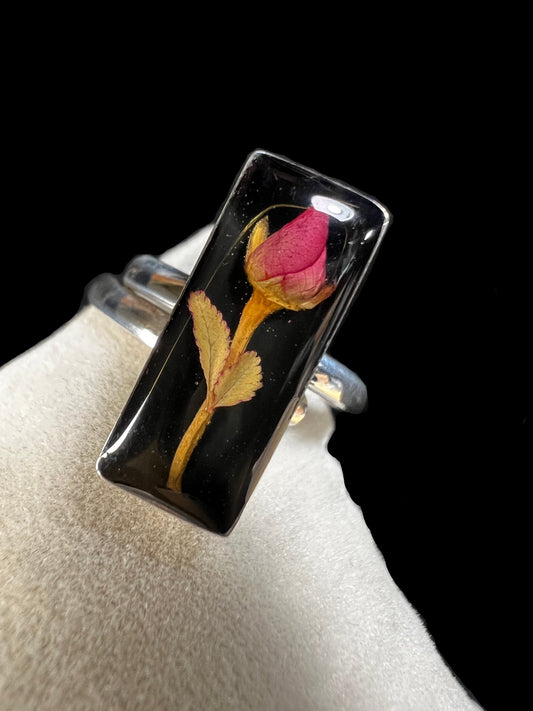 This sterling silver ring showcases a delicate natural dried flower preserved within clear resin, combining artisanal craftsmanship with timeless elegance. Ideal for those who appreciate nature-inspired jewelry with a sophisticated touch.