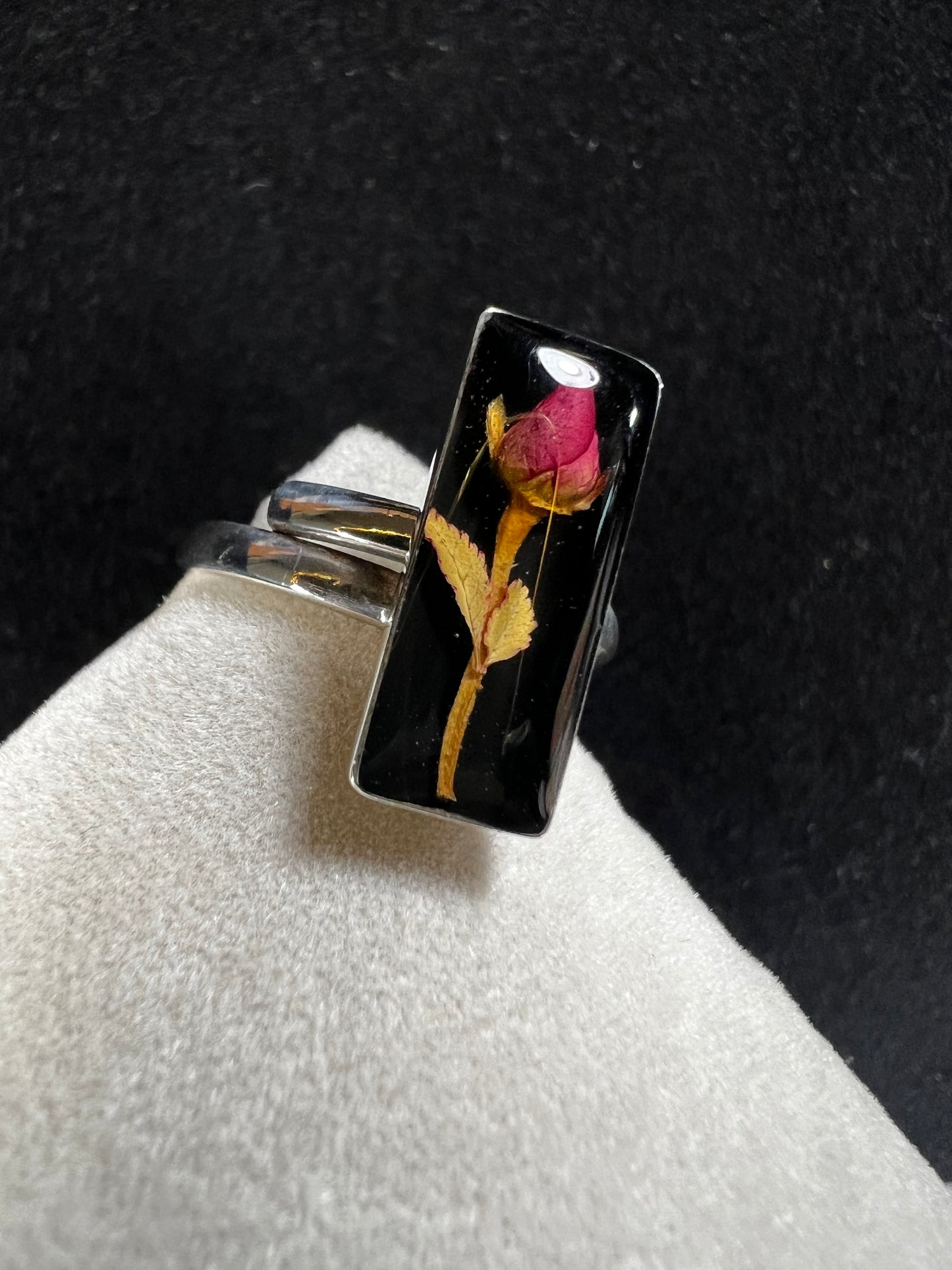 This sterling silver ring showcases a delicate natural dried flower preserved within clear resin, combining artisanal craftsmanship with timeless elegance. Ideal for those who appreciate nature-inspired jewelry with a sophisticated touch.