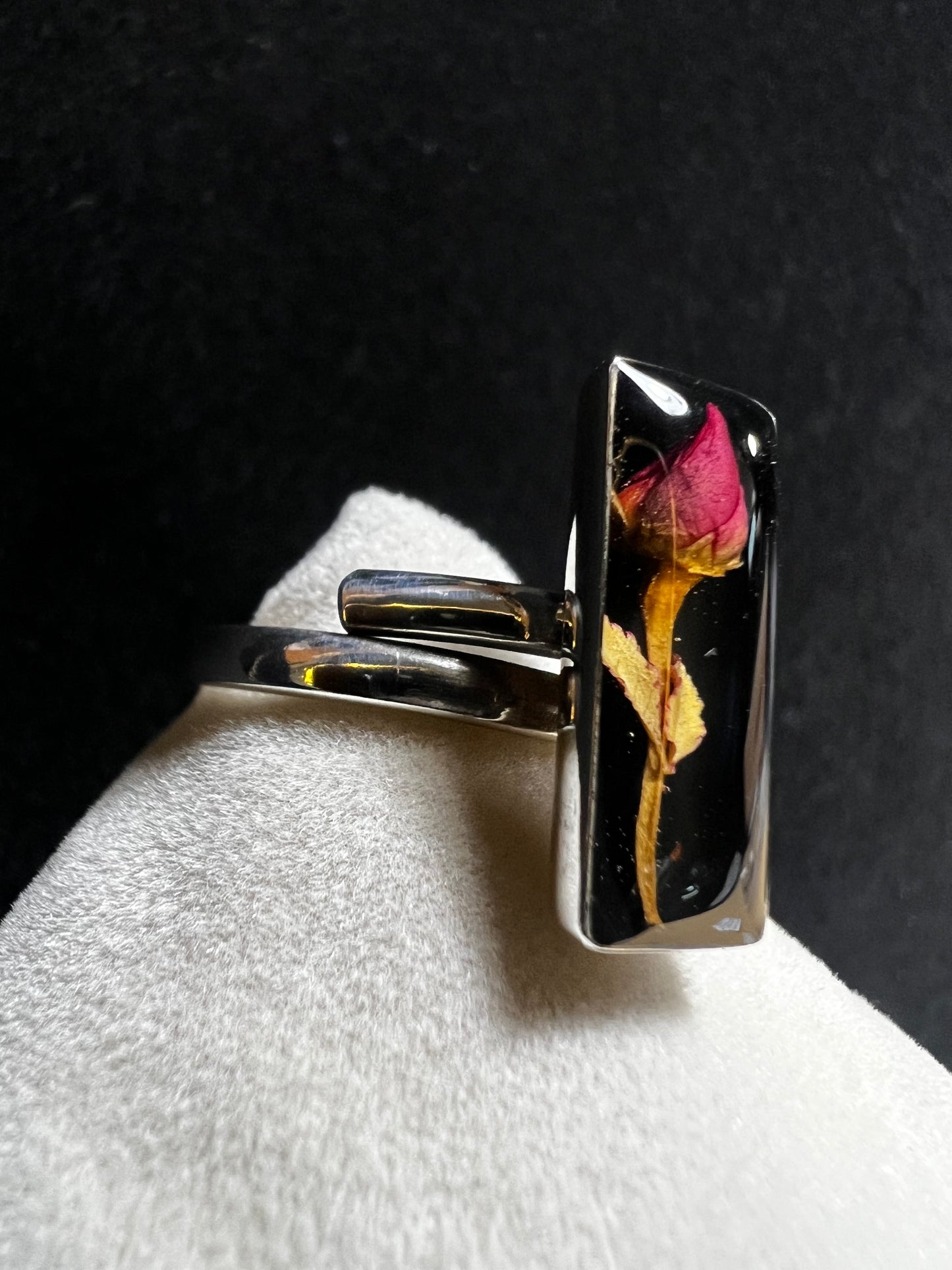 This sterling silver ring showcases a delicate natural dried flower preserved within clear resin, combining artisanal craftsmanship with timeless elegance. Ideal for those who appreciate nature-inspired jewelry with a sophisticated touch.