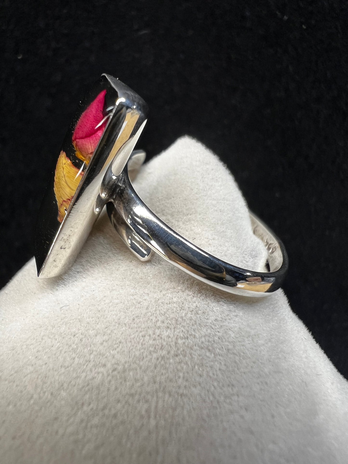 This sterling silver ring showcases a delicate natural dried flower preserved within clear resin, combining artisanal craftsmanship with timeless elegance. Ideal for those who appreciate nature-inspired jewelry with a sophisticated touch.