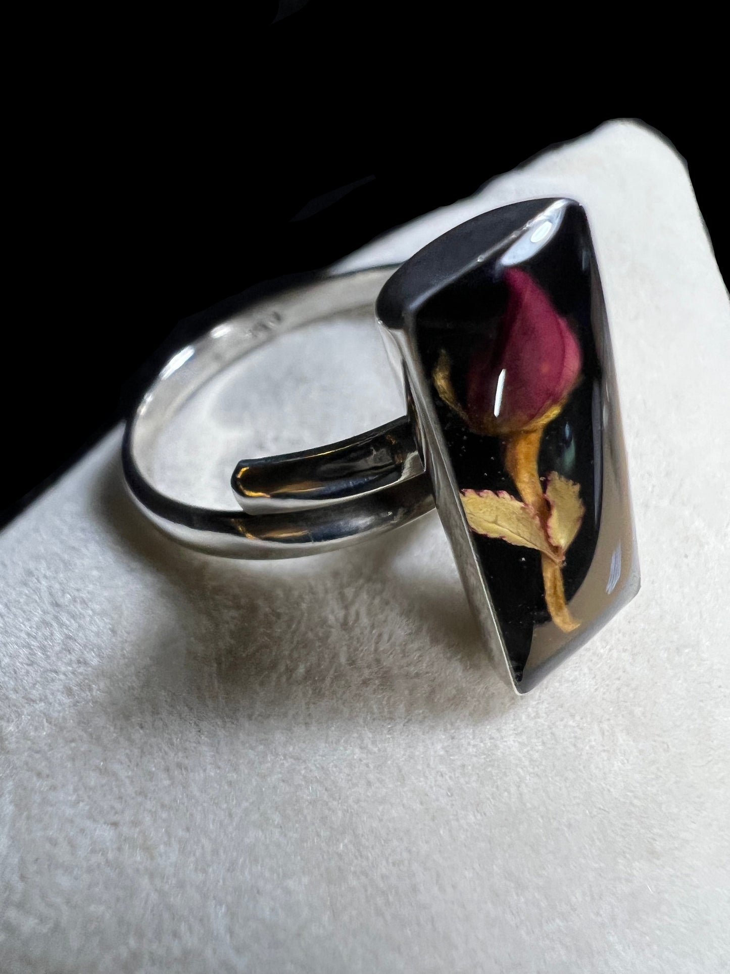 This sterling silver ring showcases a delicate natural dried flower preserved within clear resin, combining artisanal craftsmanship with timeless elegance. Ideal for those who appreciate nature-inspired jewelry with a sophisticated touch.