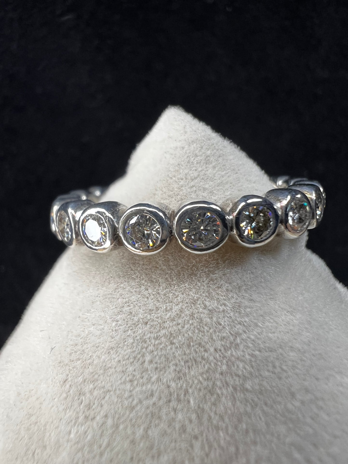 This sterling silver eternity band ring is designed with moissanite stones encircling the entire band, creating a beautiful and radiant look. Signed C&C.
