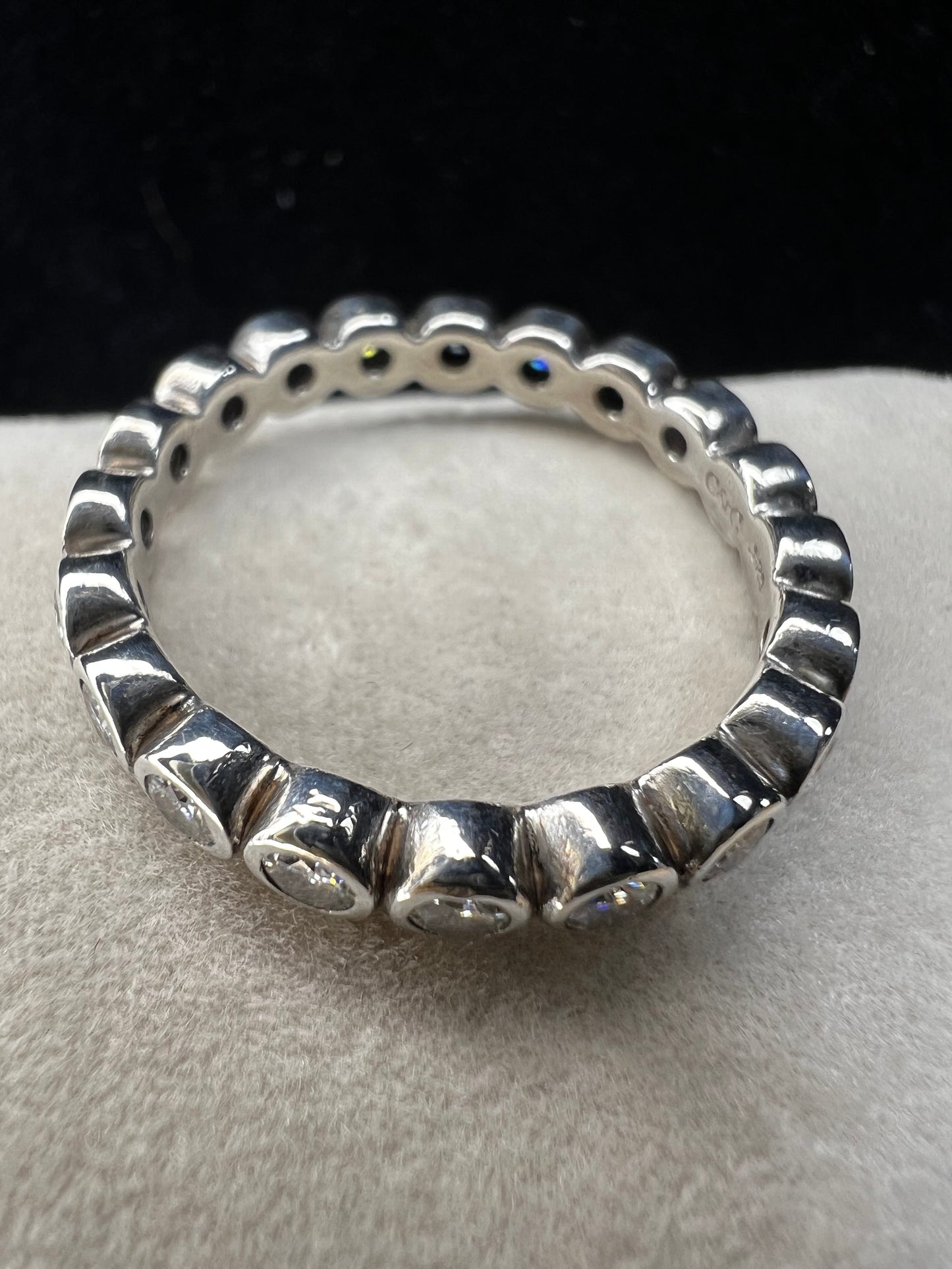 This sterling silver eternity band ring is designed with moissanite stones encircling the entire band, creating a beautiful and radiant look. Signed C&C.