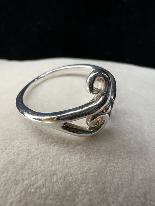 This is a simple but elegant sterling silver ring. The design features swirls that are reminiscent of ocean waves crashing on a beach.