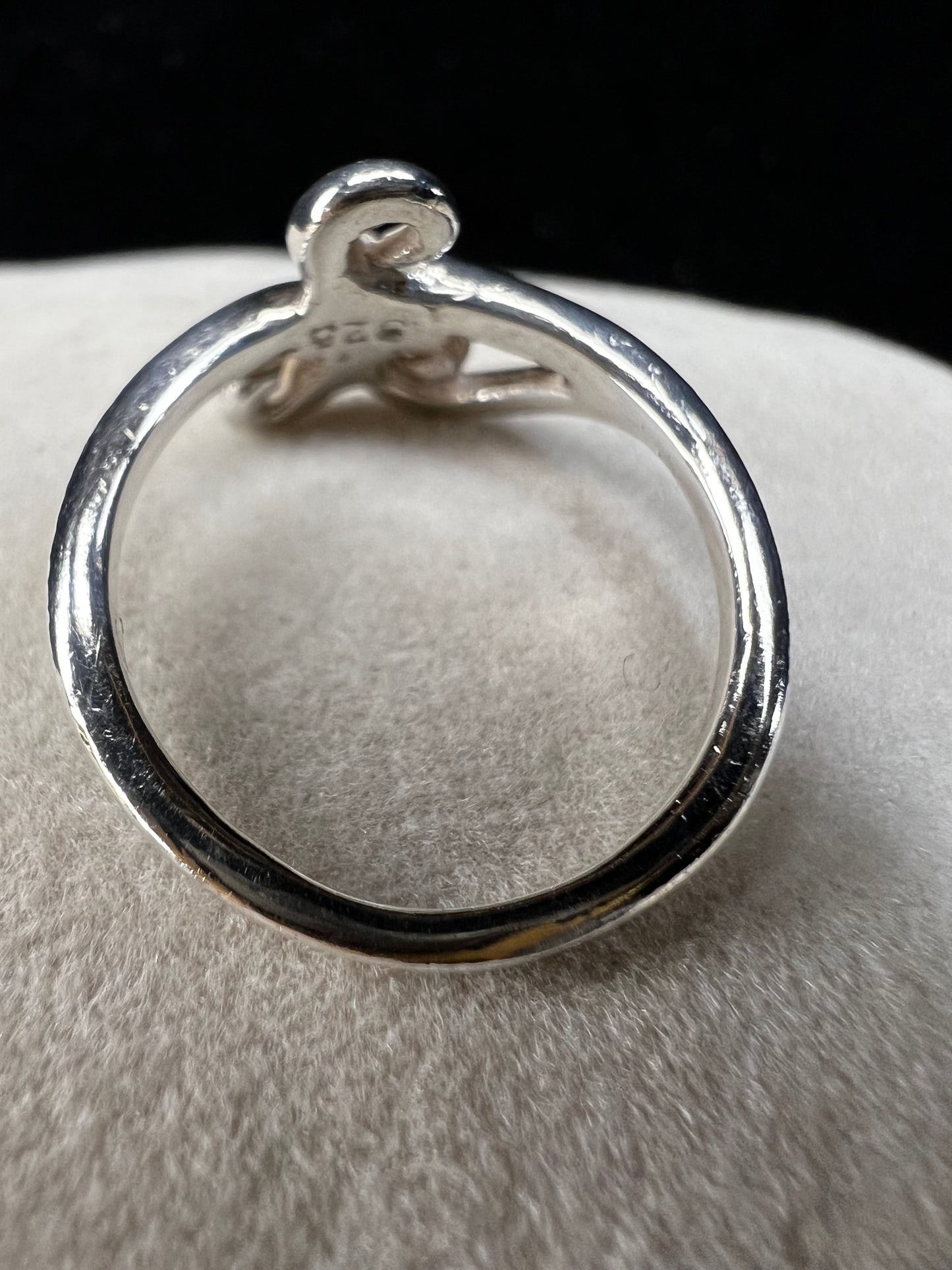 This is a simple but elegant sterling silver ring. The design features swirls that are reminiscent of ocean waves crashing on a beach.