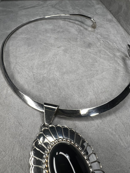 This slide pendant necklace features a large onyx and sterling pendant front and center with a sterling collar. From native American silversmith L. James.