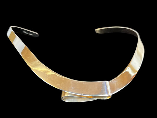 If you're looking for a necklace that embodies individuality, this is it. Crafted from fine sterling silver, this torque necklace has a unique ribbon-like fold as its focal point. This piece is signed "Dominique".