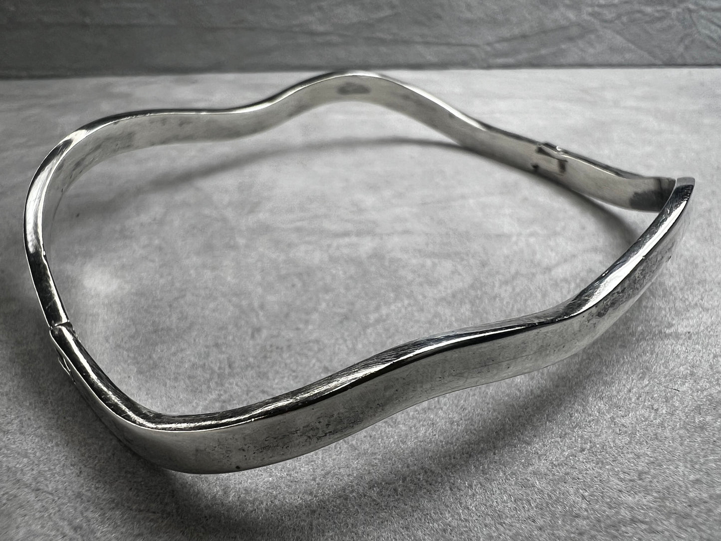This vintage Taxco sterling silver bracelet features a distinctive wavy design and is marked TM-37, showcasing authentic craftsmanship from Mexico. Its timeless style makes it a versatile accessory for everyday wear or special occasions.