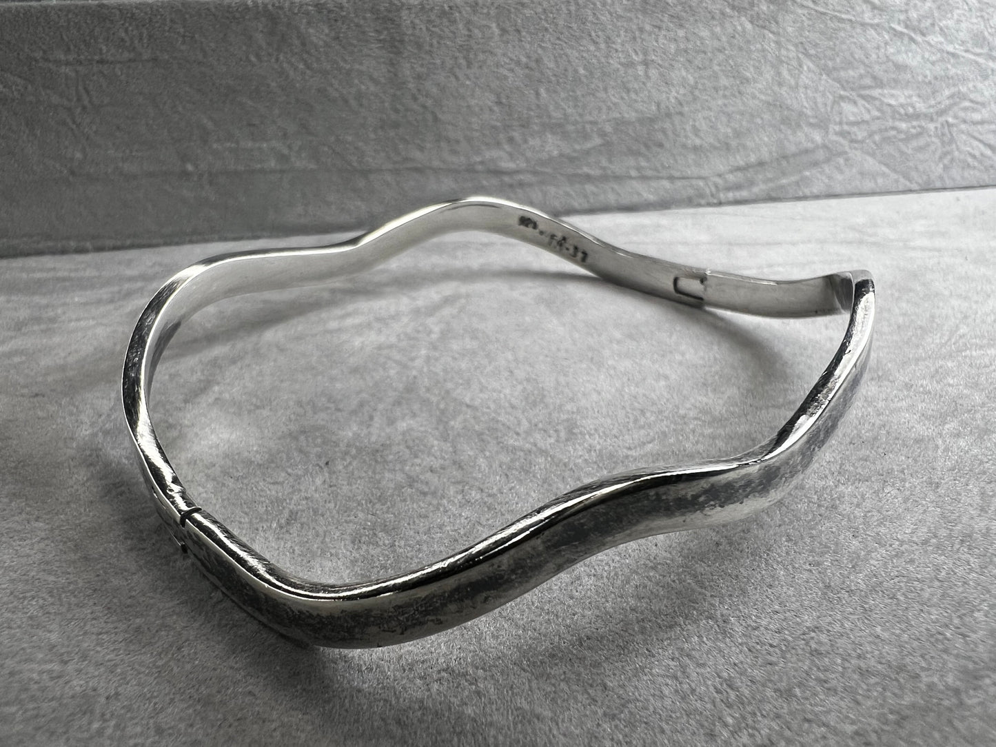 This vintage Taxco sterling silver bracelet features a distinctive wavy design and is marked TM-37, showcasing authentic craftsmanship from Mexico. Its timeless style makes it a versatile accessory for everyday wear or special occasions.
