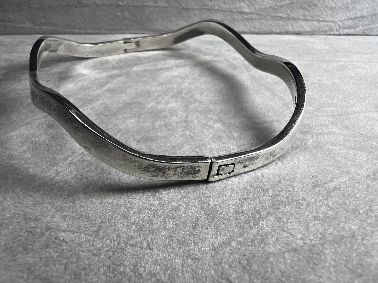 This vintage Taxco sterling silver bracelet features a distinctive wavy design and is marked TM-37, showcasing authentic craftsmanship from Mexico. Its timeless style makes it a versatile accessory for everyday wear or special occasions.
