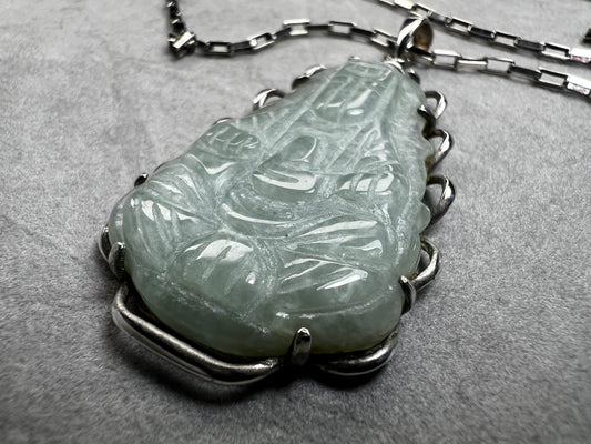 This vintage necklace combines the timeless elegance of sterling silver with the delicate beauty of a carved pastel green jade pendant. The sturdy rectangular link chain ensures durability while gracefully supporting the pendant.