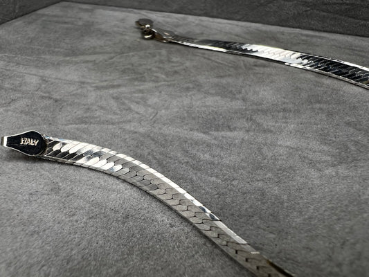 This sterling silver bracelet features a classic herringbone link design, offering a sleek and sophisticated look. It's an ideal accessory for both everyday wear and special occasions.