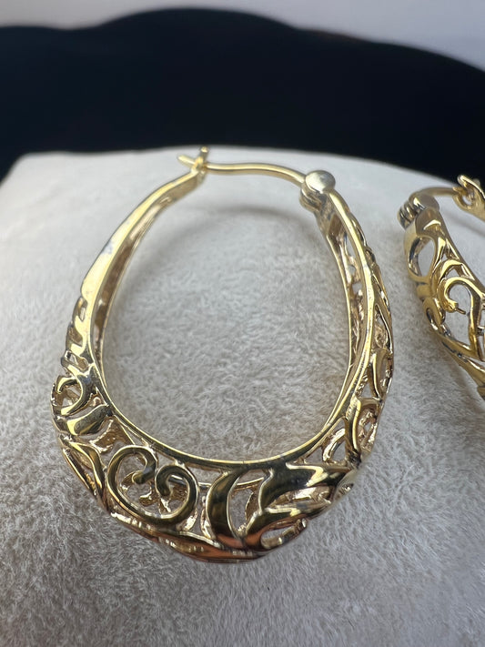 These beautiful filigree-design earrings are crafted of sterling silver with a gold overlay. The oval hoop design will add a touch of class to any outfit.