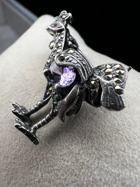 This is a striking mid-century rooster brooch that captures vintage elegance and whimsy. Handcrafted in sterling silver, this statement piece features a vibrant amethyst belly, accented with shimmering marcasite details that catch the light. Perfect for adding character to any outfit or displaying as a collectible treasure.