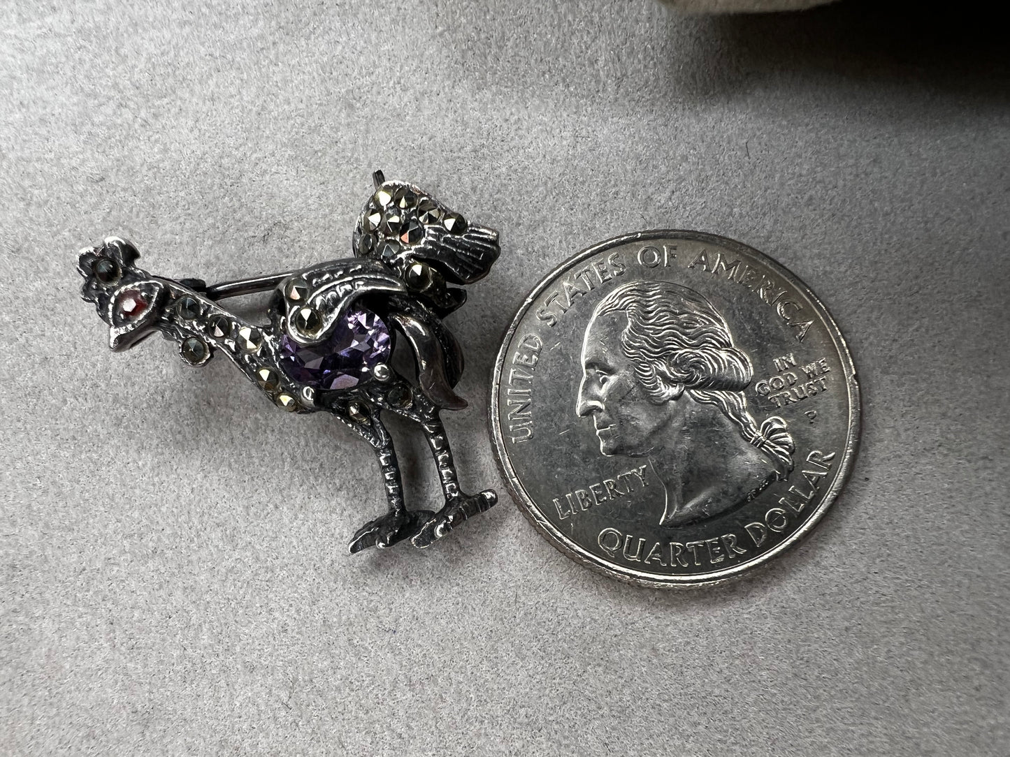 This is a striking mid-century rooster brooch that captures vintage elegance and whimsy. Handcrafted in sterling silver, this statement piece features a vibrant amethyst belly, accented with shimmering marcasite details that catch the light. Perfect for adding character to any outfit or displaying as a collectible treasure.