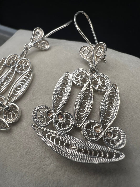These sterling silver filigree earrings showcase intricate craftsmanship, offering a distinctive and elegant accessory. Their delicate design adds a refined touch to any outfit, making them ideal for those seeking subtle sophistication with a unique flair.
