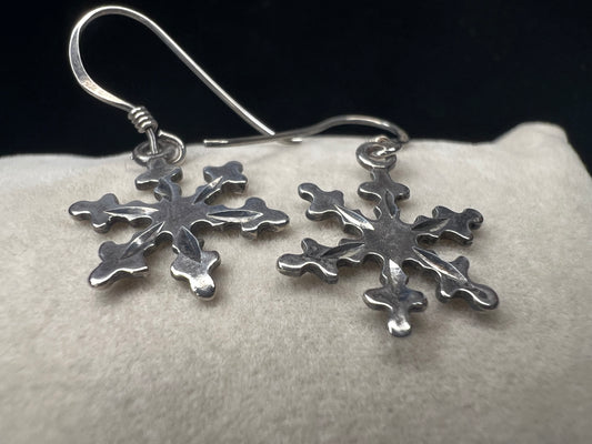 These sterling silver earrings feature intricate texture on both sides of each snowflake, designed to catch and reflect light with every movement. Ideal for complementing winter outfits, they offer a subtle yet elegant touch of seasonal charm.