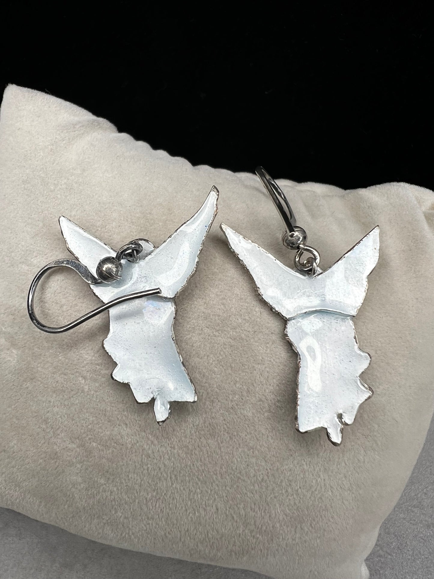 These sterling silver enameled angel earrings combine expert craftsmanship with delicate design. Perfect for those seeking a meaningful accessory, these earrings offer both elegance and a subtle symbol of protection and grace.