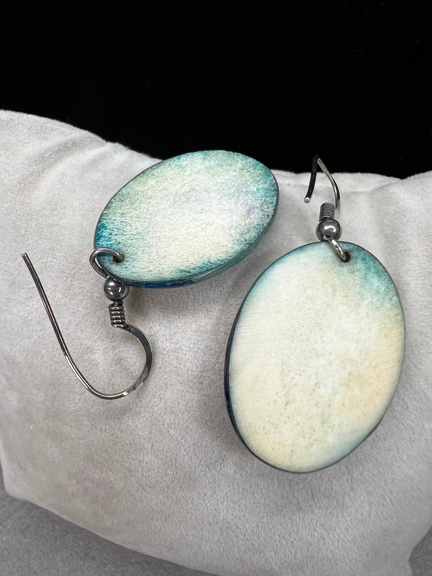 These vintage handmade earrings showcase a vibrant native scene on a lightweight material, expertly crafted to highlight intricate details and rich colors. They are completed with sterling silver hooks.