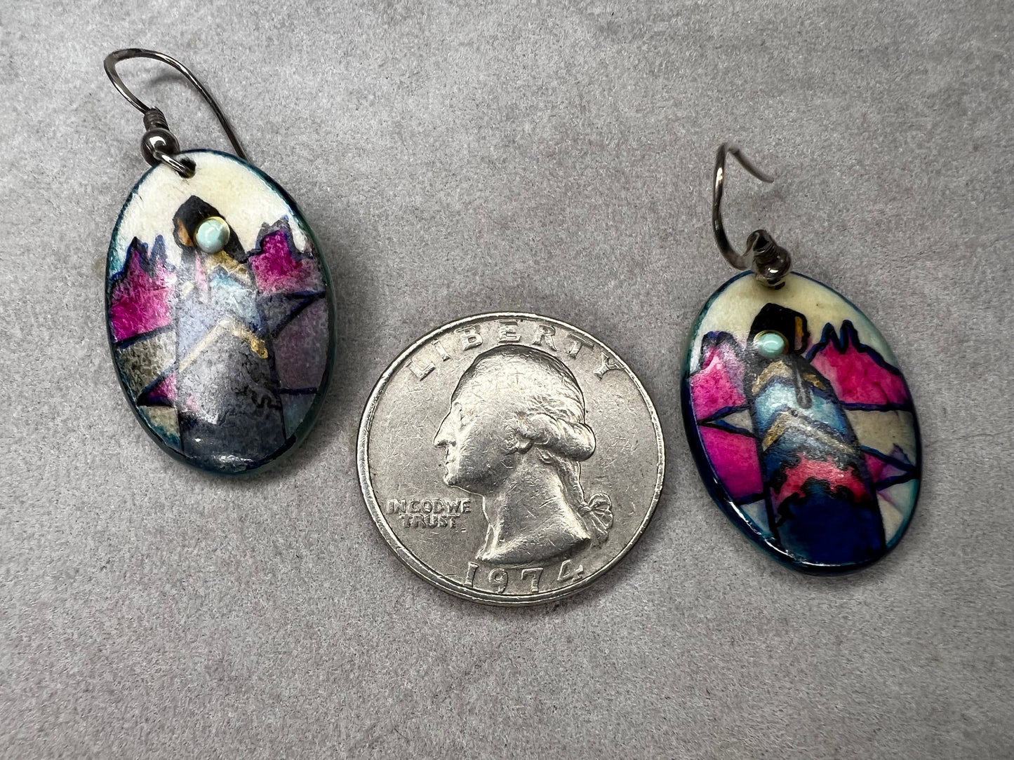 These vintage handmade earrings showcase a vibrant native scene on a lightweight material, expertly crafted to highlight intricate details and rich colors. They are completed with sterling silver hooks.