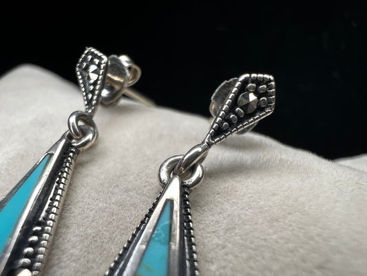 These sterling silver dangle earrings combine the timeless elegance of marcasite with the vibrant appeal of faux turquoise. They are an ideal accessory for adding vintage-inspired sophistication to any outfit.
