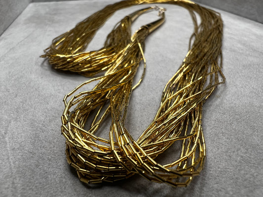 This is a striking gold over sterling silver necklace, featuring the iconic liquid-sterling design. The fluid, sculptural form creates visual movement and dimension, while the gold overlay adds warmth and luxury to the cool brilliance of sterling silver. With substantial length and thickness, this piece commands attention as a standalone statement.