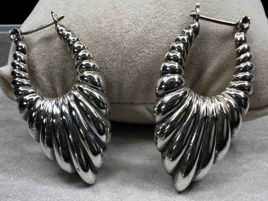 These vintage sterling silver scalloped shrimp hoop earrings are a distinctive accessory that complements any vintage-inspired ensemble. Ideal for collectors and enthusiasts seeking authentic vintage charm.