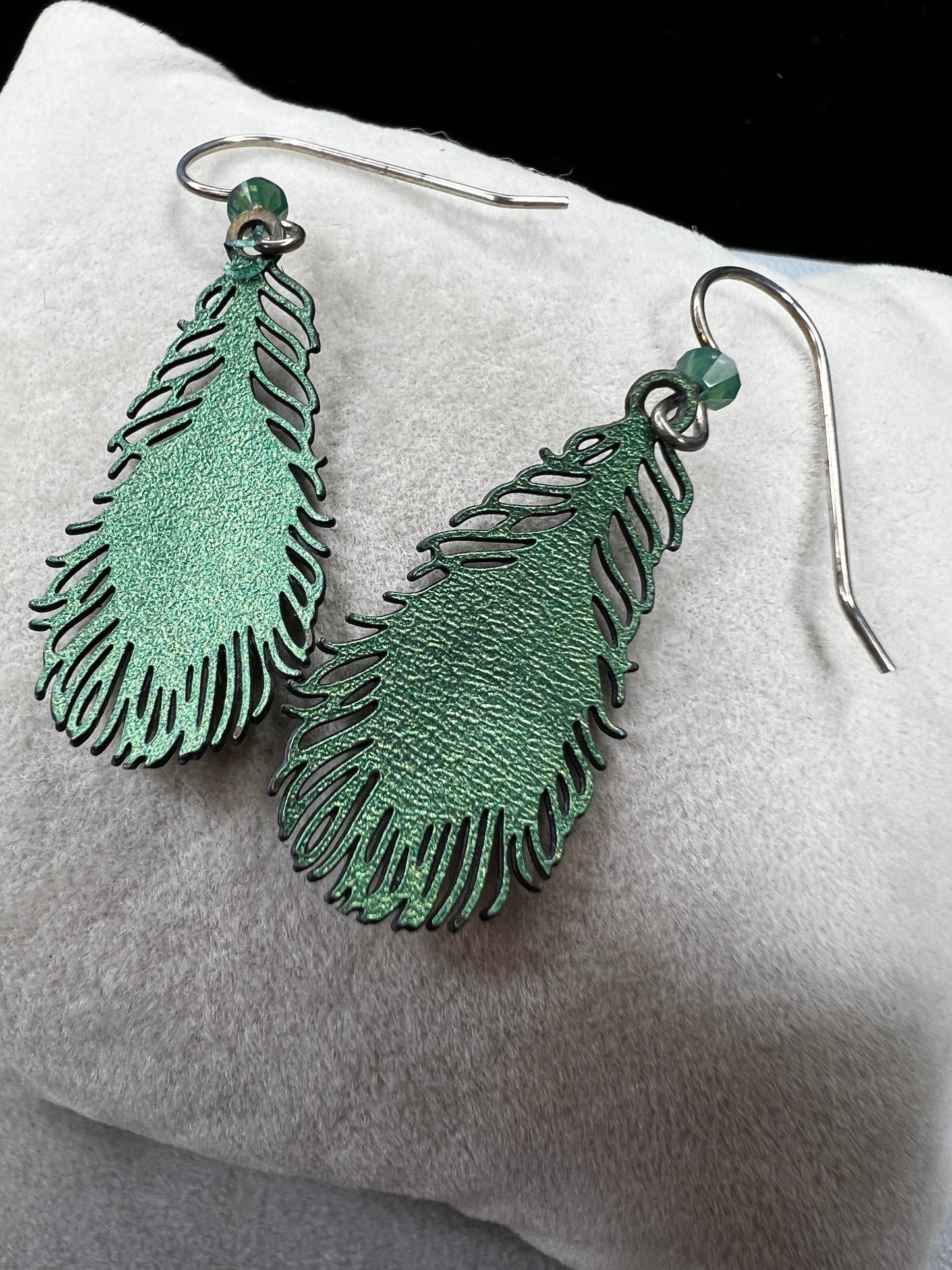 These sterling silver earrings showcase a unique design inspired by peacock feathers, enhanced with vibrant enamel detailing.