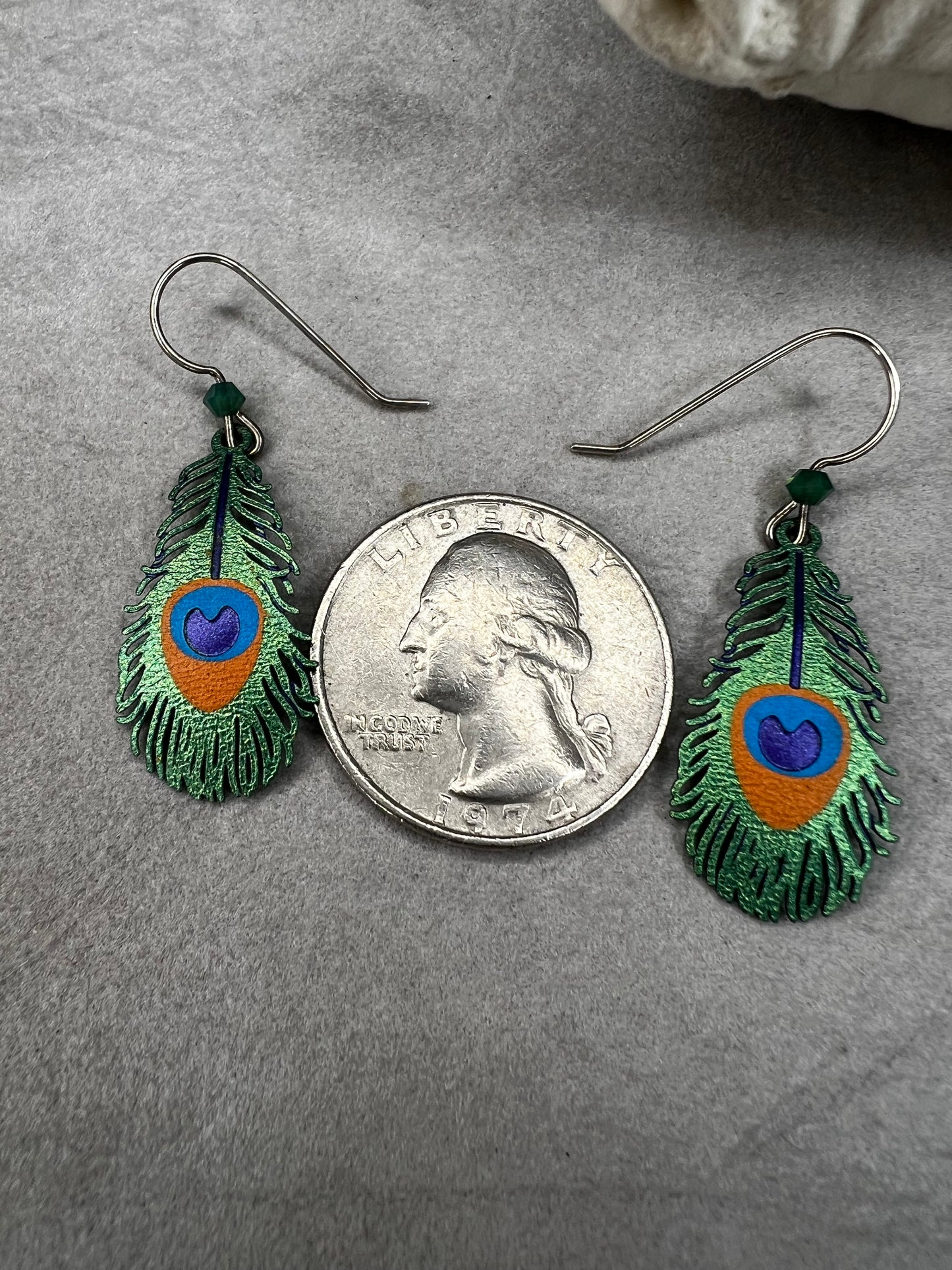 These sterling silver earrings showcase a unique design inspired by peacock feathers, enhanced with vibrant enamel detailing.