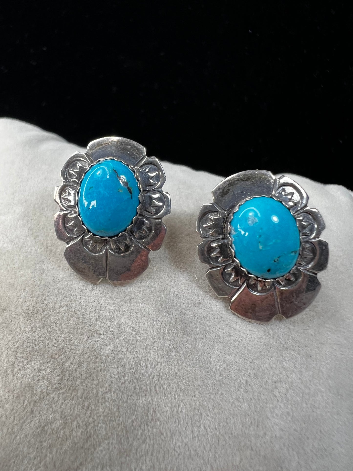 These sterling silver earrings showcase expertly crafted faux turquoise stones, set within intricately detailed silver settings. Signed LS.