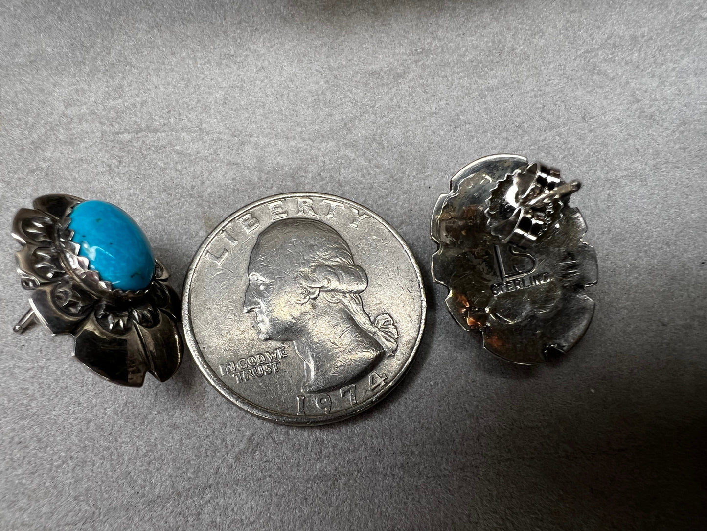 These sterling silver earrings showcase expertly crafted faux turquoise stones, set within intricately detailed silver settings. Signed LS.
