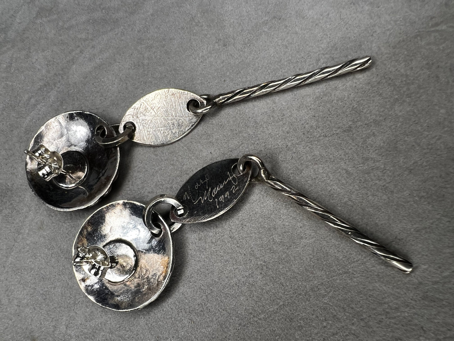 These sterling silver dangle earrings feature a distinctive 3-inch length and are signed by the designer, ensuring authenticity and exclusivity. Their elegant design complements both casual and formal attire.