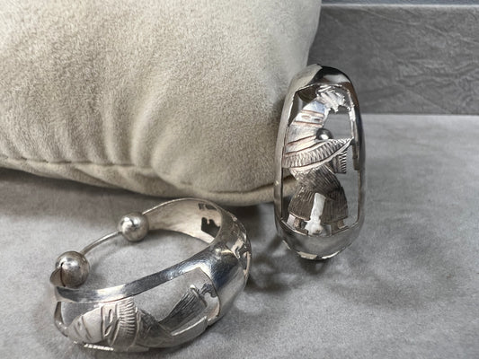 These vintage sterling silver hoop earrings showcase intricate cut-out silhouettes, blending classic design with artistic detail. Perfect for adding a subtle yet distinctive touch to any outfit.