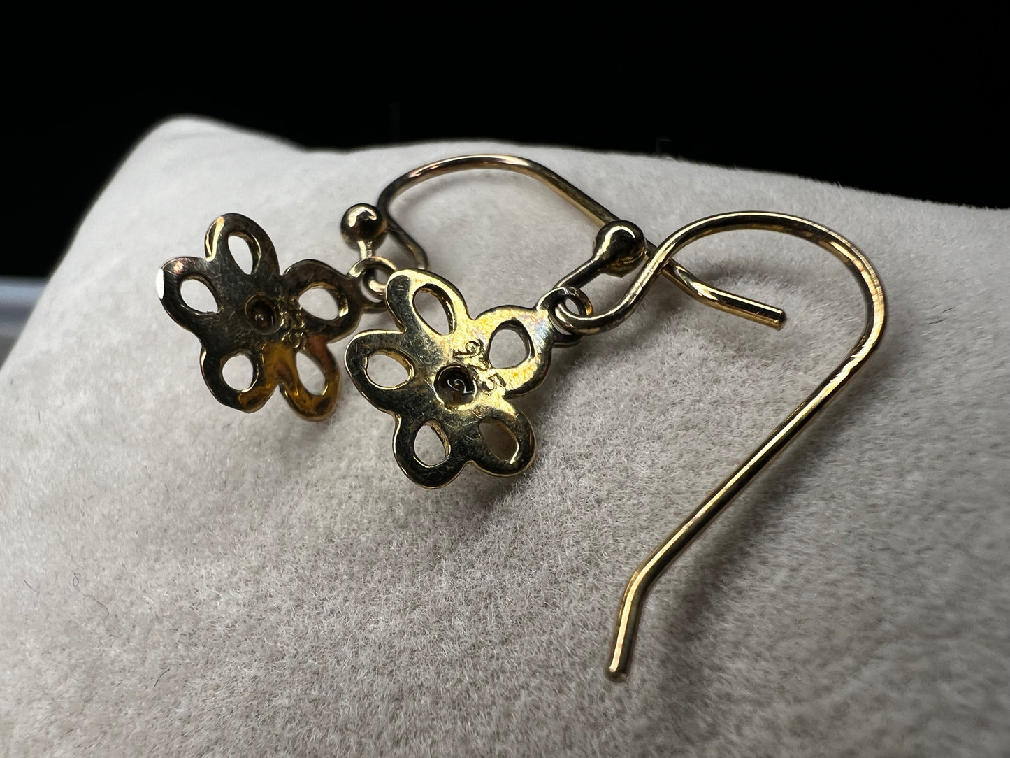 Crafted from sterling silver with a gold overlay, these earrings feature a small flower that hangs just below the ear.