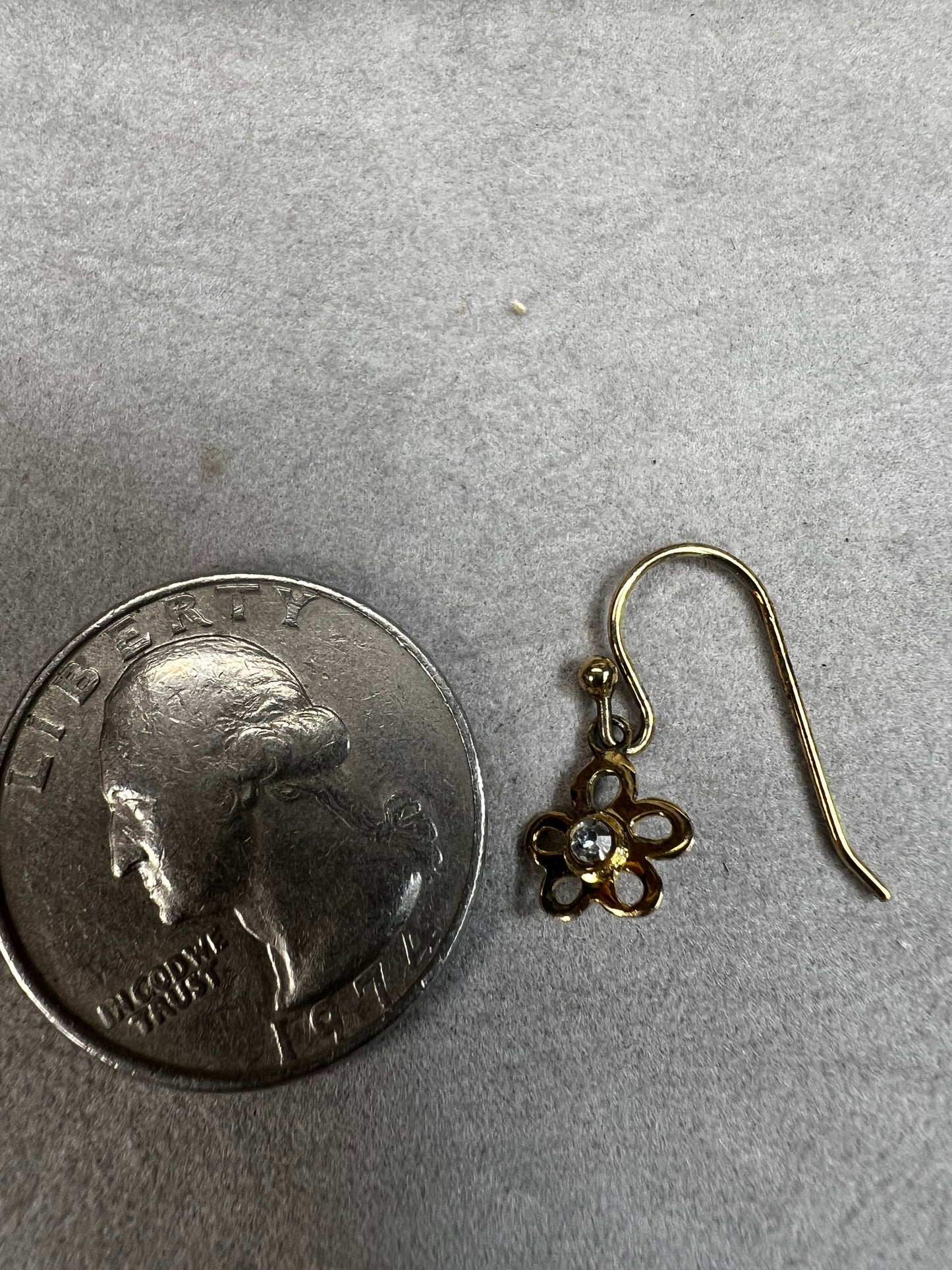 Crafted from sterling silver with a gold overlay, these earrings feature a small flower that hangs just below the ear.
