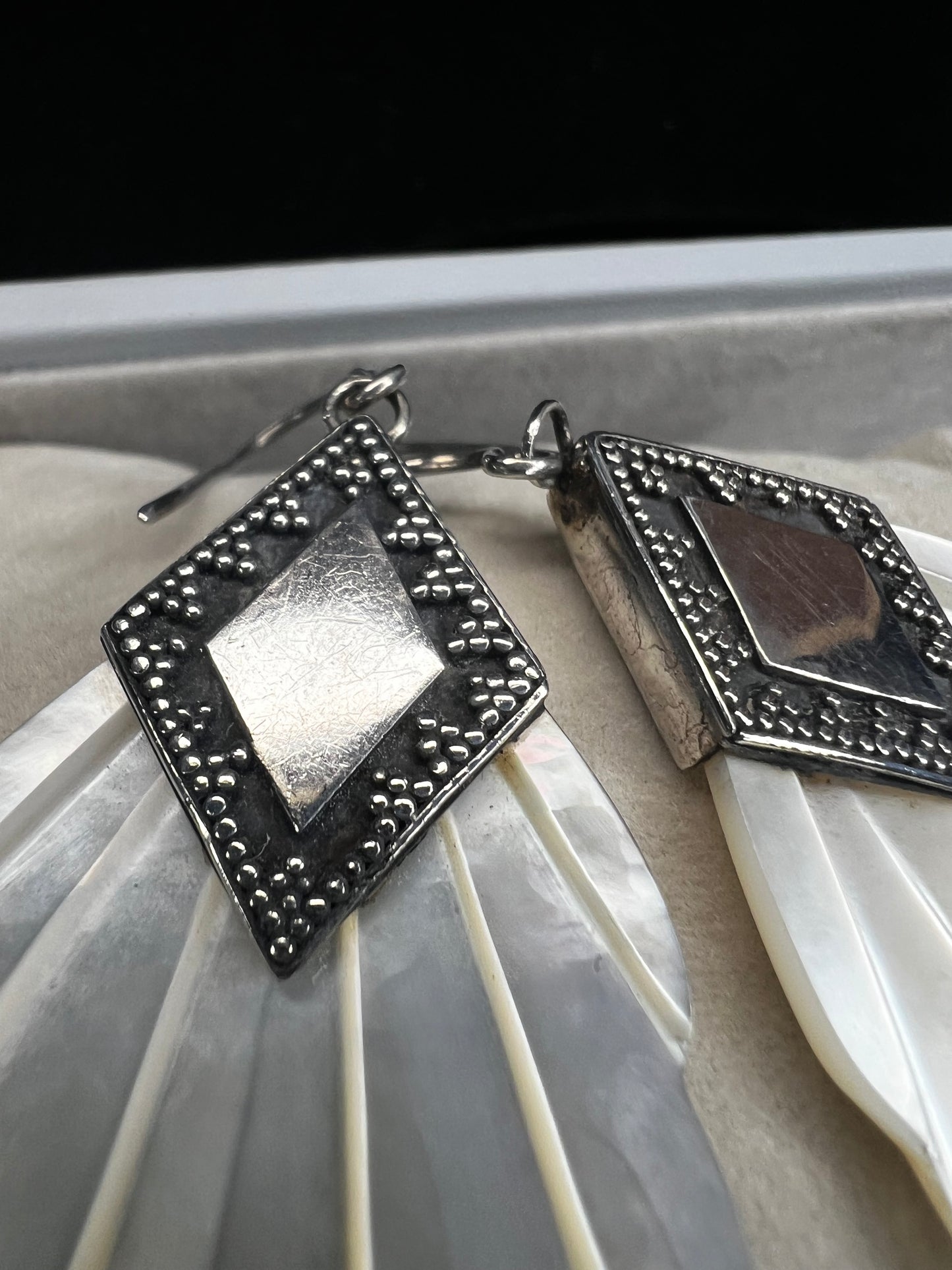 Crafted from sterling silver and mother of pearl, these vintage earrings measure about 3 inches long, making a bold and elegant statement.
