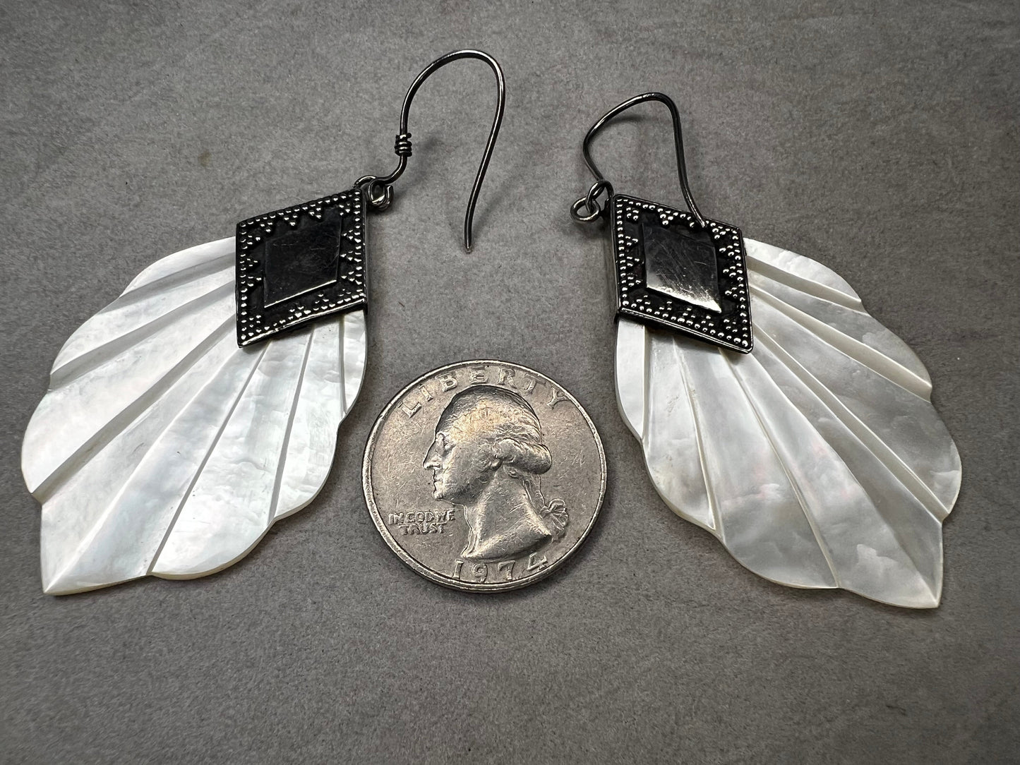 Crafted from sterling silver and mother of pearl, these vintage earrings measure about 3 inches long, making a bold and elegant statement.