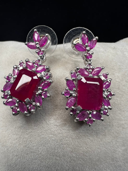 These sterling silver earrings feature a striking large ruby centerpiece, elegantly framed by sparkling topaz stones. Crafted with lab-created gems, they offer a luxurious look at a more accessible price point.