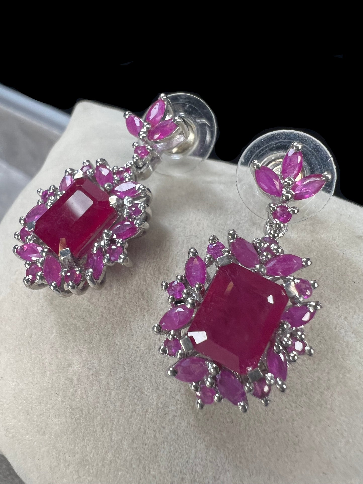 These sterling silver earrings feature a striking large ruby centerpiece, elegantly framed by sparkling topaz stones. Crafted with lab-created gems, they offer a luxurious look at a more accessible price point.