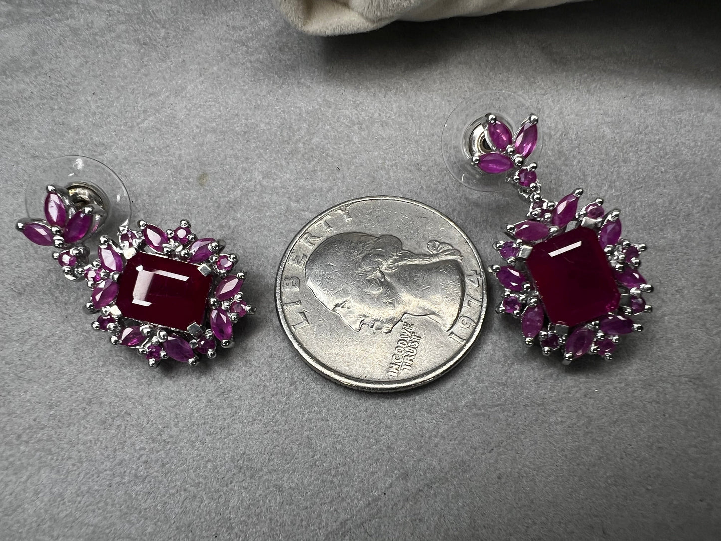 These sterling silver earrings feature a striking large ruby centerpiece, elegantly framed by sparkling topaz stones. Crafted with lab-created gems, they offer a luxurious look at a more accessible price point.