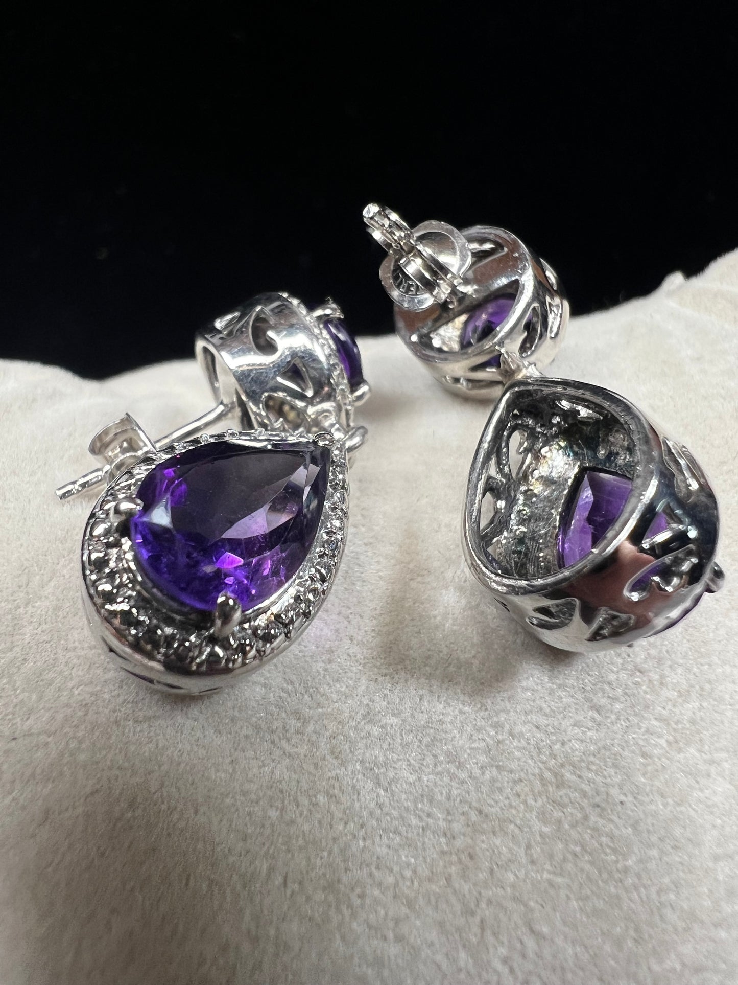 These sterling silver and amethyst drop earrings combine elegant design with quality craftsmanship. Perfect for adding a subtle pop of color to any outfit.
