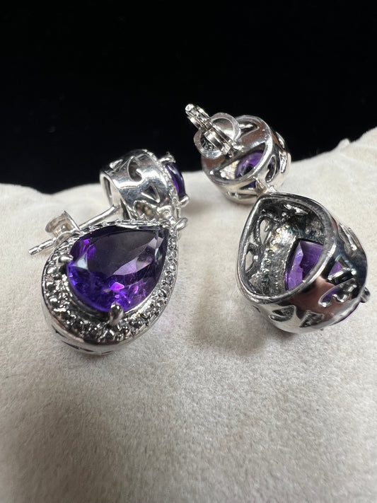 These sterling silver and amethyst drop earrings combine elegant design with quality craftsmanship. Perfect for adding a subtle pop of color to any outfit.