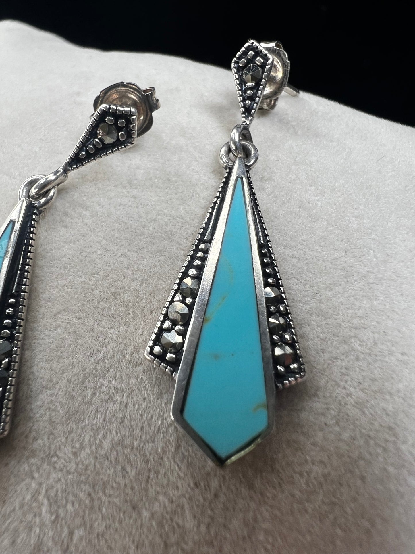 These sterling silver dangle earrings combine the timeless elegance of marcasite with the vibrant appeal of faux turquoise. They are an ideal accessory for adding vintage-inspired sophistication to any outfit.