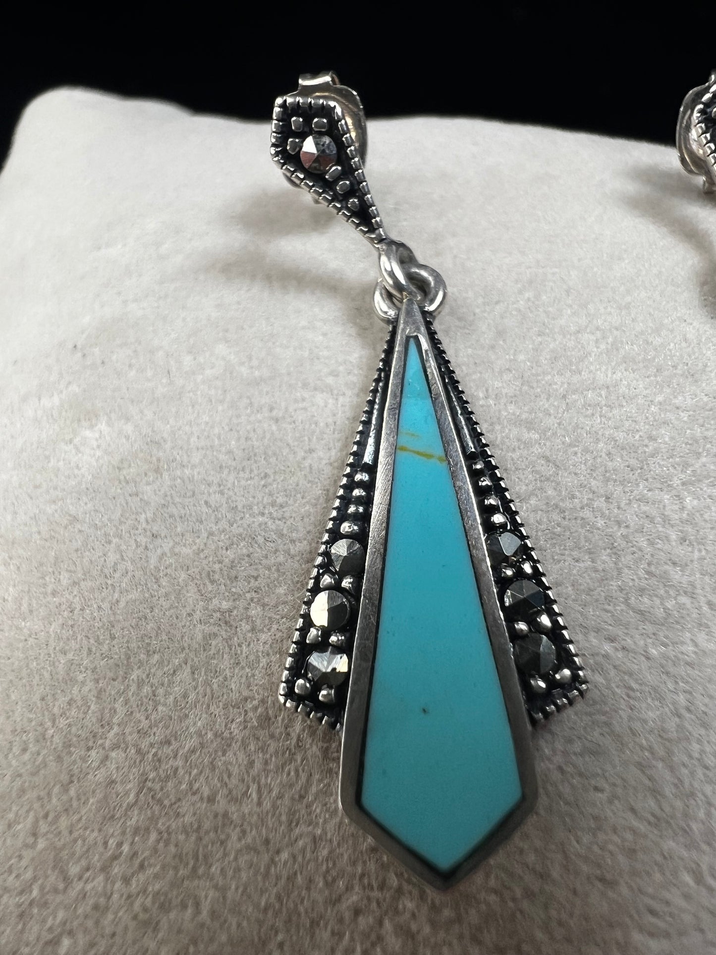 These sterling silver dangle earrings combine the timeless elegance of marcasite with the vibrant appeal of faux turquoise. They are an ideal accessory for adding vintage-inspired sophistication to any outfit.