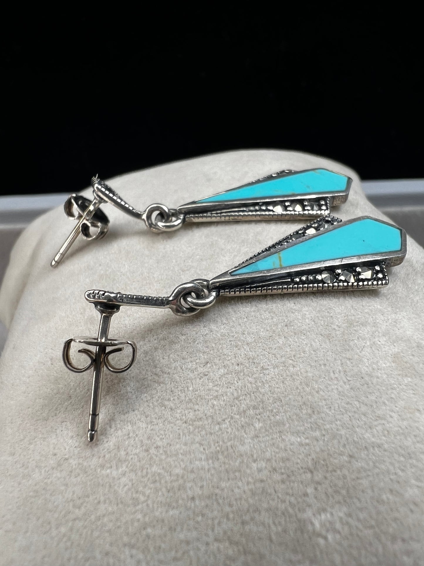 These sterling silver dangle earrings combine the timeless elegance of marcasite with the vibrant appeal of faux turquoise. They are an ideal accessory for adding vintage-inspired sophistication to any outfit.