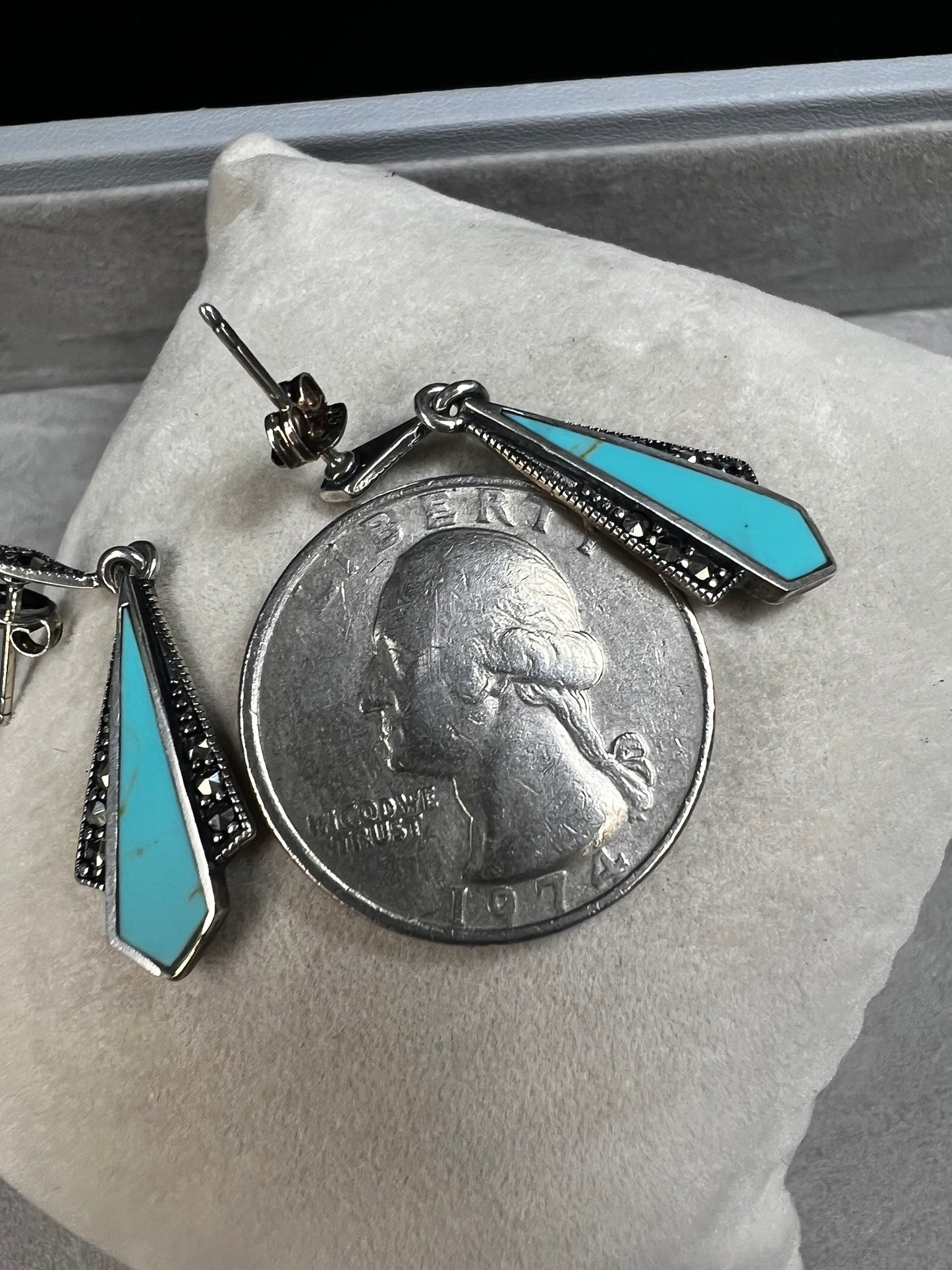 These sterling silver dangle earrings combine the timeless elegance of marcasite with the vibrant appeal of faux turquoise. They are an ideal accessory for adding vintage-inspired sophistication to any outfit.