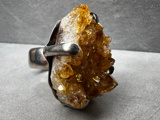 This sterling silver ring showcases a striking citrine specimen, expertly set to highlight its natural beauty. The warm, golden hues of the citrine contrast elegantly with the polished silver band, creating a sophisticated piece that commands attention.
