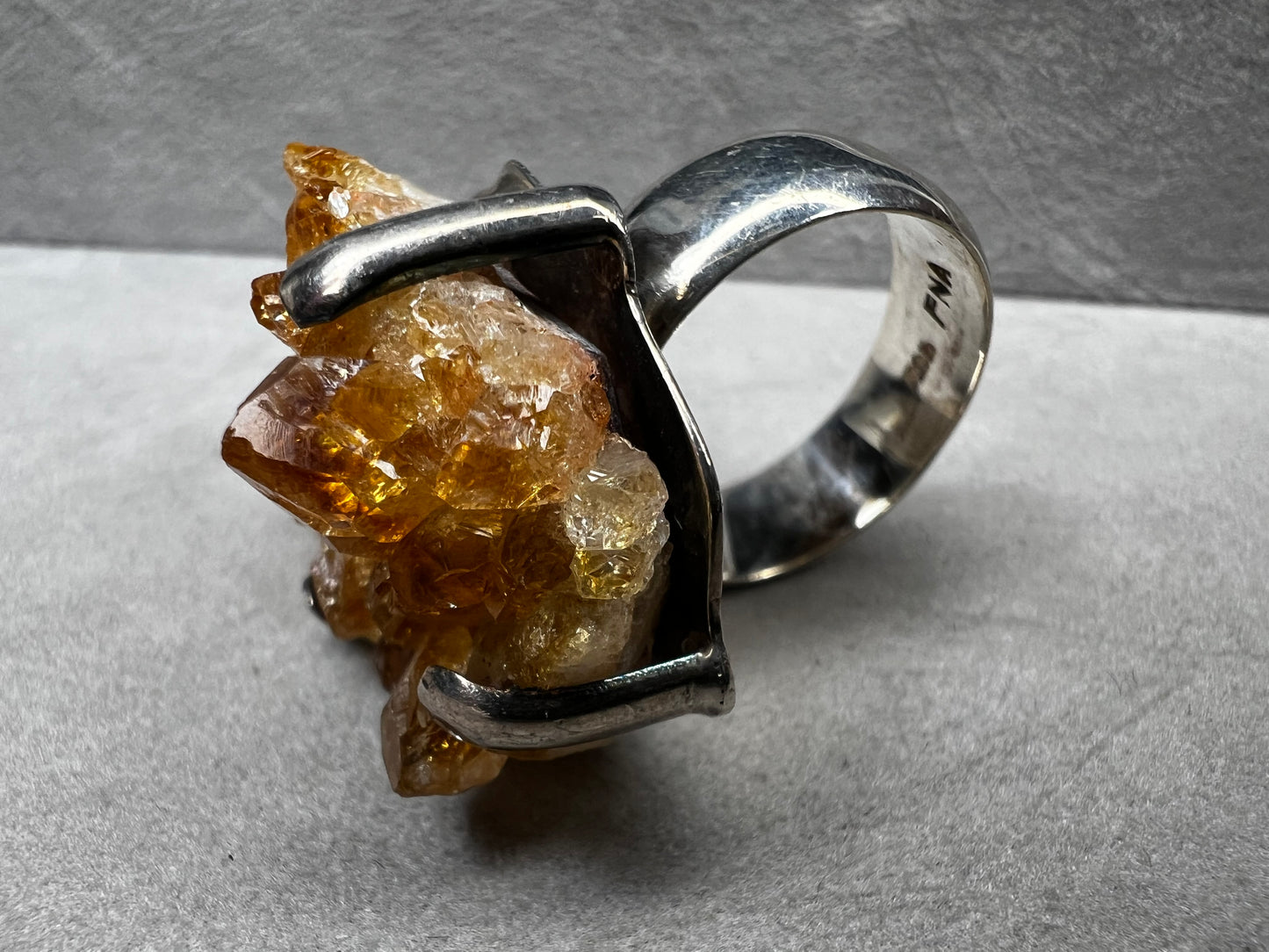This sterling silver ring showcases a striking citrine specimen, expertly set to highlight its natural beauty. The warm, golden hues of the citrine contrast elegantly with the polished silver band, creating a sophisticated piece that commands attention.