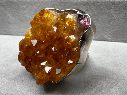 This sterling silver ring by Charles Albert showcases a striking 1 1/4" citrine specimen, combining expert craftsmanship with bold design. The large citrine centerpiece offers vibrant color and natural beauty, making it a distinctive accessory that will elevate any ensemble with refined elegance.
